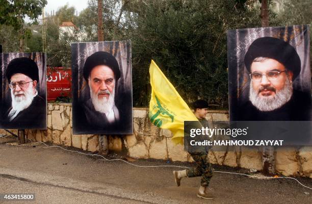 Lebanese boy runs holding a Hezbollah flag past the portraits of Iran's Supreme Leader Ayatollah Ali Khamenei , founder of Iran's Islamic Republic,...