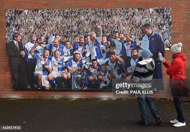 Blackburn supporters study a poster showing the celebrating 1994-1995 title-winning team ahead of English FA Cup fifth round football match between...