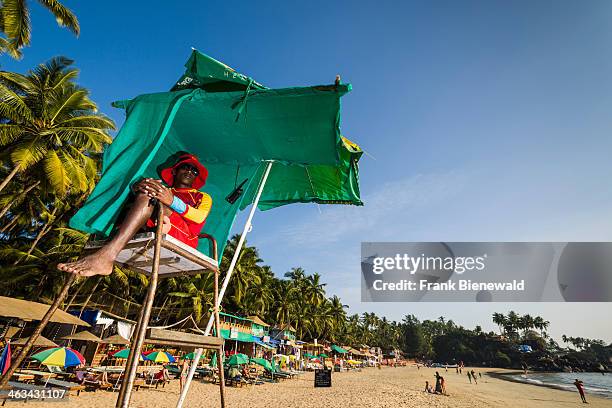 Life guard is sitting and watching at Palolem Beach with blue sky, palm trees and white sand.