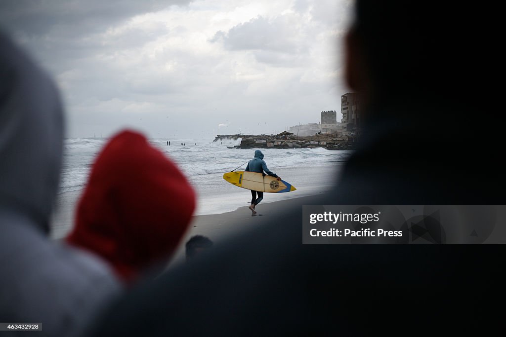 A Palestinian prepares his surfboard as he wades in the...