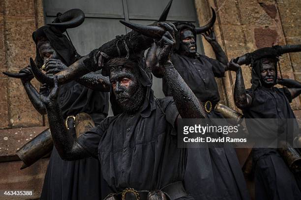 People with their face covered in oil and soot and carrying bull horns representing a devil join a carnival festival on February 14, 2015 in Luzon,...