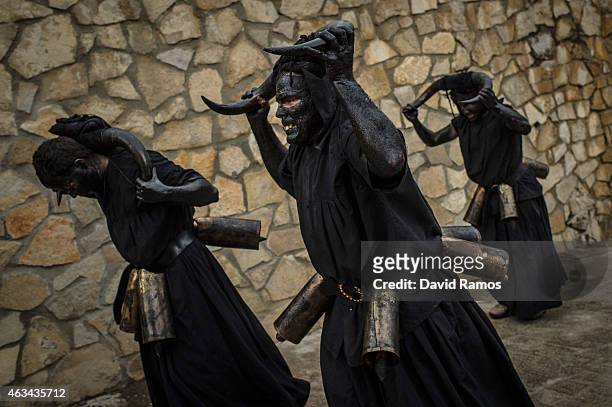 People with his face covered in oil and soot and carrying bull horns representing a devil join a carnival festival on February 14, 2015 in Luzon,...
