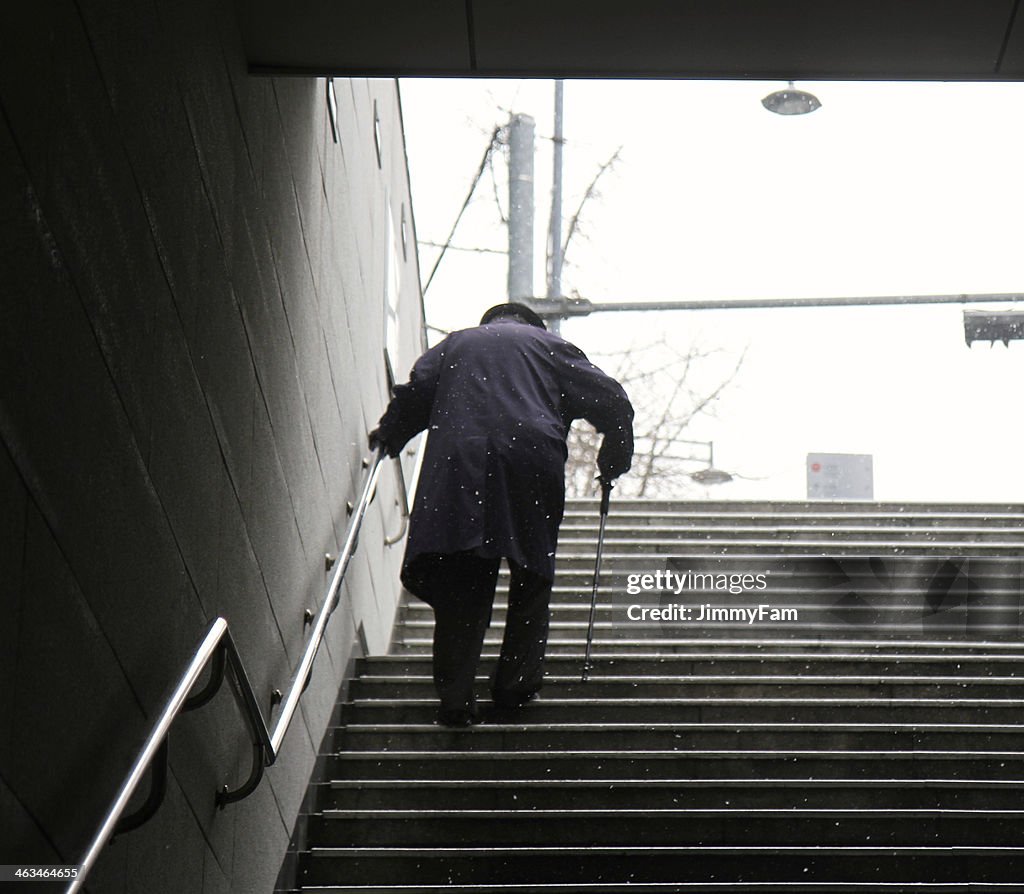 Elderly Man walking up a set of stairs during winter