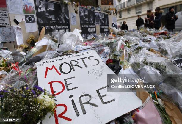 People pay homage outside the headquarters of French satirical weekly Charlie Hebdo in Paris on February 15 next to flowers layed in memory of...