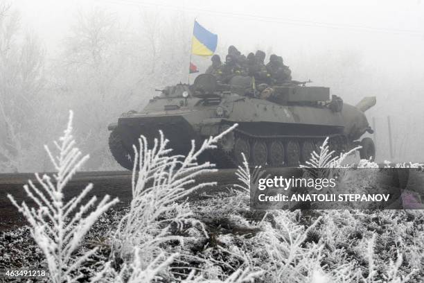 Ukrainian servicemen ride on a tank along a road from Artemivsk to Debaltseve on February 15, 2015 A ceasefire in Ukraine was cautiously observed by...
