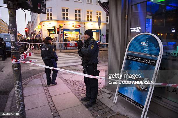 Armed police stand guard outside an internet cafe that was raided in connection with the twin attack on a freedom of expression meeting and the main...