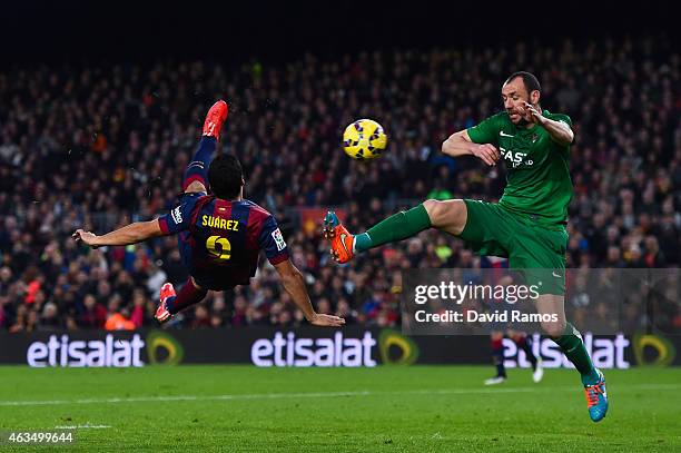 Luis Suarez of FC Barcelona scores his team's fifth goal under a challenge by Ivan Ramis of Levante UD during the La Liga match between FC Barcelona...