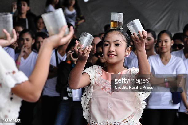 Young female performer balances a glass on top of her head as she dances a Filipino folk dance as part of the activities during during the Pasinaya...