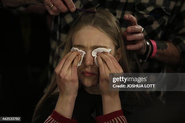 Model removes her make-up as her hair is styled backstage before presenting a creation from the Prabal Gurung Fall/Winter collection during New York...