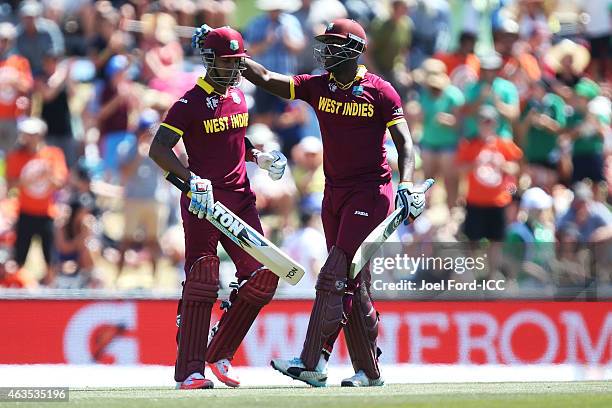 Lendl Simmons of the West Indies is congratulated by teammate Andre Russell after scoring a century during the 2015 ICC Cricket World Cup match...