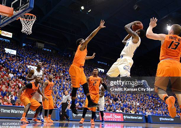 Kansas' Naadir Tharpe shoots in the lane as Oklahoma State's Stevie Clark, left, and Phil Forte defend at Allen Fieldhouse in Lawrence, Kan., on...