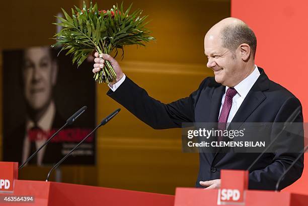 Hamburg's mayor Olaf Scholz of the Social Democrats party holds flowers during a press statement on February 16, 2015 in Berlin a day after regional...