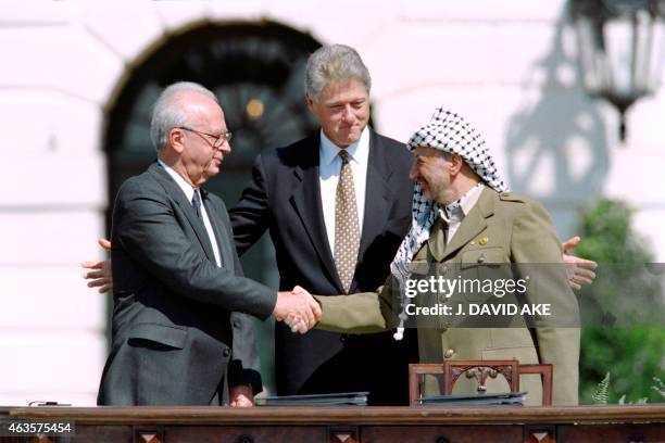 President Bill Clinton stands between PLO leader Yasser Arafat and Israeli Prime Minister Yitzahk Rabin as they shake hands for the first time, on...