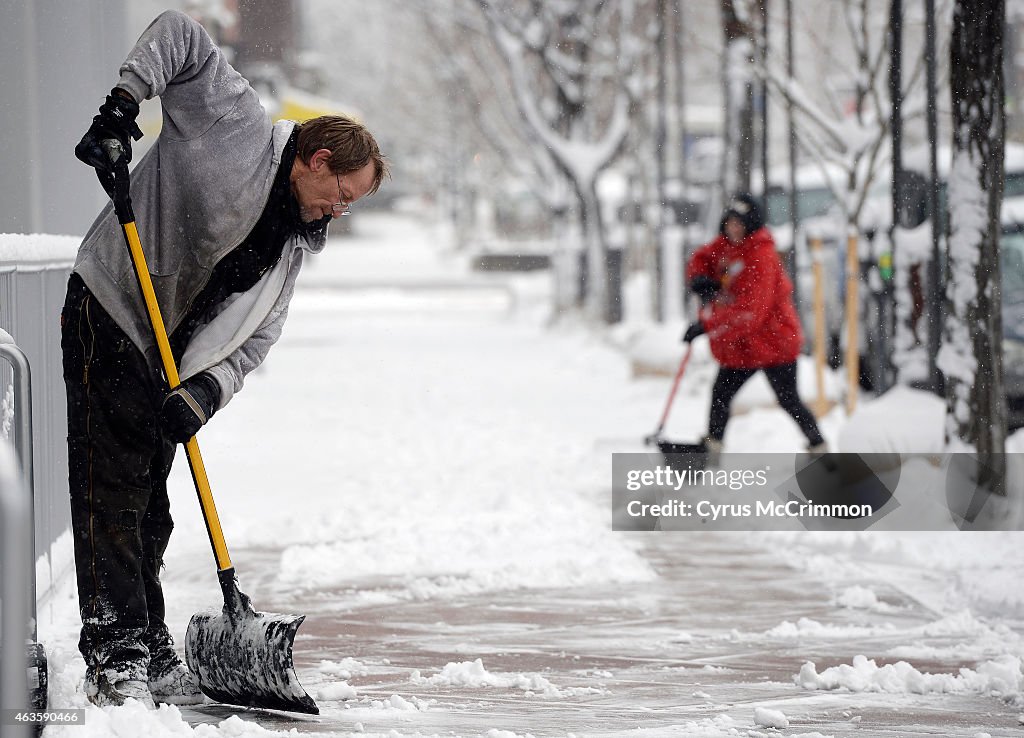 Snow hit the Denver metro area  and Darren Charter, left, with Starla Evey, in the background, shovel along Second Avenue in Cherry Creek North  at Milwaukee Street.