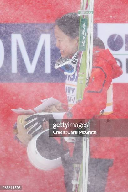 Sara Takanashi of Japan shields herself from a sudden snow gust during the victory ceremony after the Normal Hill Individual Final Round during the...