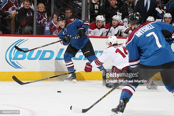 Zach Redmond of the Colorado Avalanche passes to teammate John Mitchell as Joe Vitale of the Arizona Coyotes defends at the Pepsi Center on February...