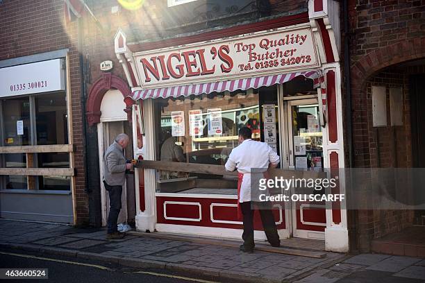 Butcher helps board up his shop before the opposing teams of the Up'ards and the Down'ards compete in the annual game of Royal Shrovetide Football in...