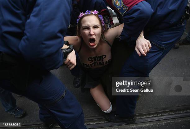 Bare-breasted Femen protester demonstrating against the scheduled visit of Russian President Vladimir Putin is detained by police near the Parliament...