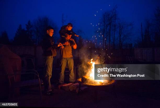 Marine Cpl. Beau Wise Ryan Walton left and Luke Wise, 3 warm up next to an outdoor fire at Traci's home on February 2, 2013 in Puyallup, Wa. Jean and...