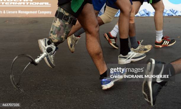 Indian runner Devender Singh runs with a prosthetic blade as he takes part in the Mumbai Marathon on January 19, 2014. Thousands of people turned out...