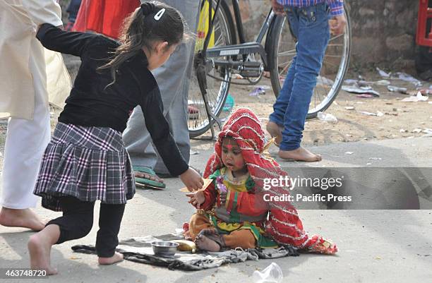 Female Indian street child dressed as a Kanjak, a Hindu female deity, begs outside a temple during Shivratri celebrations in Jammu.