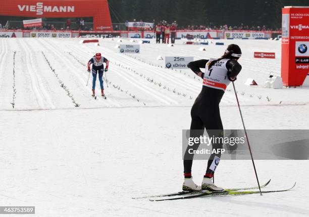 Poland's Justyna Kowalczyk watches Russia's Yulia Tchekaleva arrive at the finishing line of the 10km mass start classic in the FIS Cross Country...
