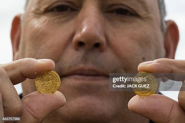 Man holds two of the gold coins recently found on the seabed off Israel's Mediterranean coast, in the Israeli town of Caesarea, on February 18, 2015....
