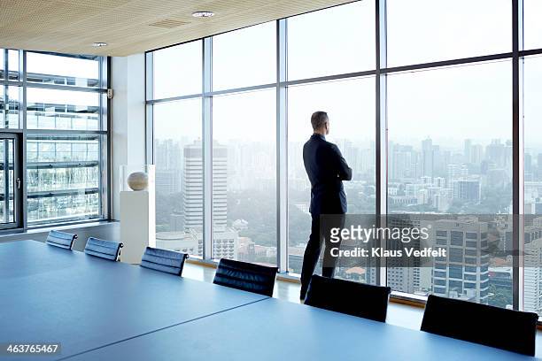 businessman looking out of window watching skyline - attesa foto e immagini stock
