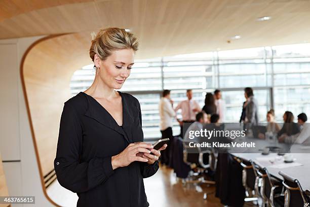 businesswoman using smartphone in conference room - well dressed stock pictures, royalty-free photos & images