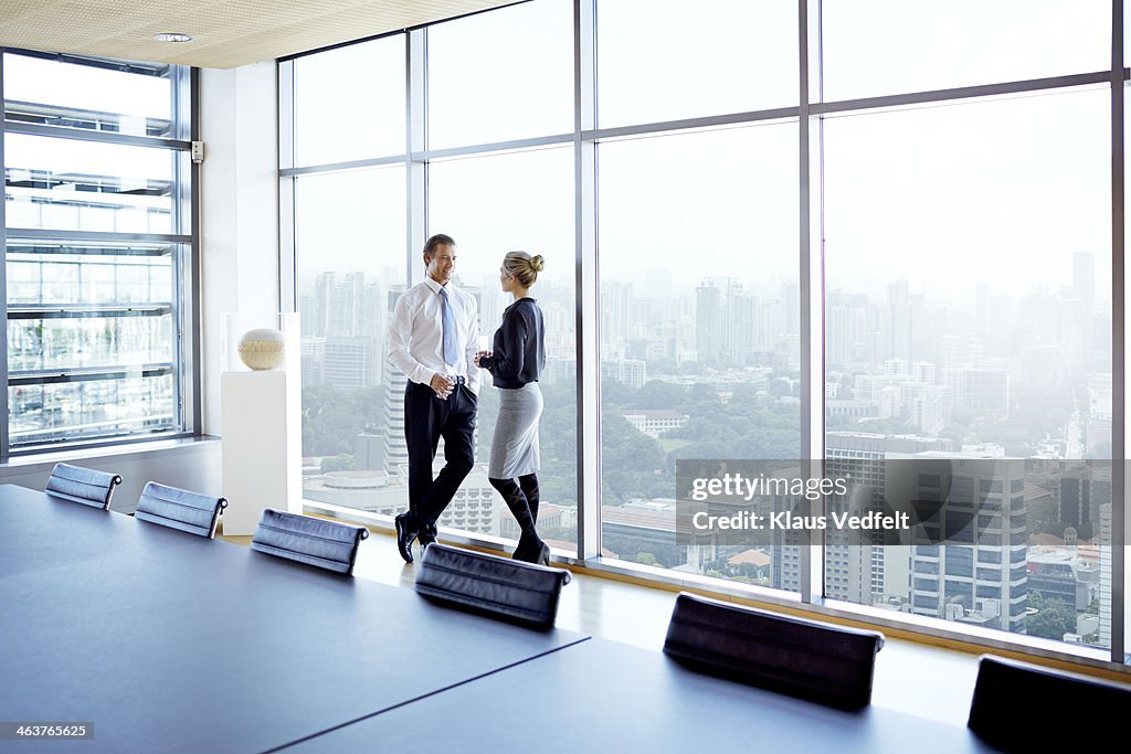 Businessman & woman standing by big windows