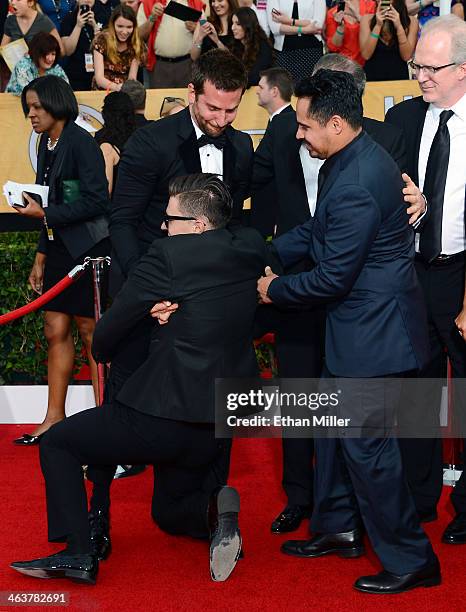 Actor Michael Pena tries to help actor Bradley Cooper remove Ukrainian reporter and prankster Vitalii Sediuk from Cooper's legs on the red carpet at...