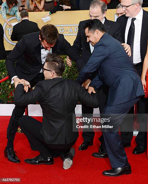 Actor Michael Pena tries to help actor Bradley Cooper remove Ukrainian reporter and prankster Vitalii Sediuk from Cooper's legs on the red carpet at...