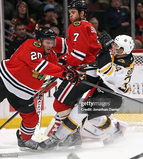 Carl Soderberg of the Boston Bruins collides with Brandon Saad and Brent Seabrook of the Chicago Blackhawks at the United Center on January 19, 2014...