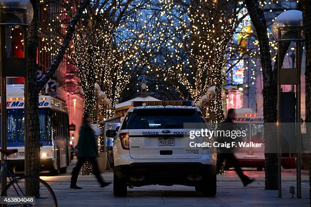 Pedestrians pass a police officer stationed on the 16th Street Mall in Denver, CO February 04, 2015.