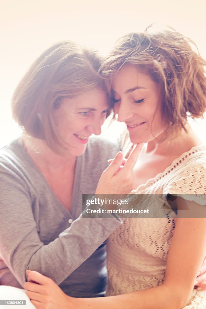 Portrait of real mature mother and adult daughter, backlit.