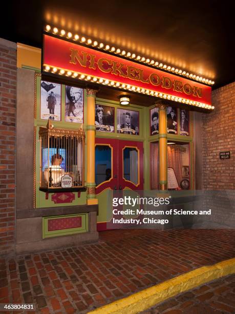 An image of the box office and marquee of the Nickelodeon movie theater with black and white silent movie posters with famous actors, in the...