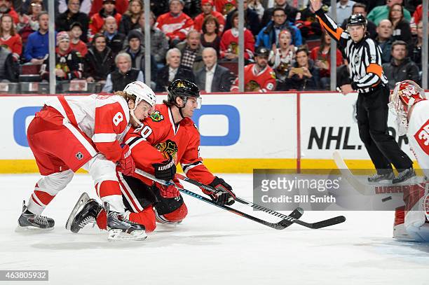 Goalie Jimmy Howard of the Detroit Red Wings blocks the shot taken by Brandon Saad of the Chicago Blackhawks as Justin Abdelkader reaches from behind...