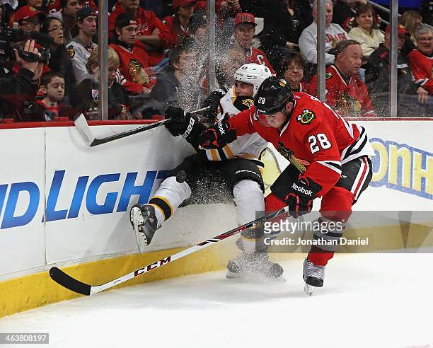 Ben Smith of the Chicago Blackhawks checks Torey Krug of the Boston Bruins as they battle for the puck at the United Center on January 19, 2014 in...