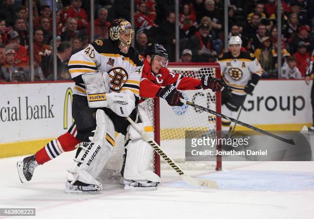 Jonathan Toews of the Chicago Blackhawks squeezes past Tuukka Rask of the Boston Bruins after Rast cleared the puck at the United Center on January...
