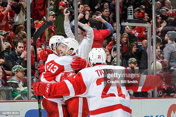 Pavel Datsyuk and Tomas Tatar celebrate with Darren Helm of the Detroit Red Wings after Helm scored against the Chicago Blackhawks in the third...