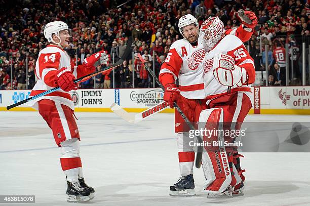 Gustav Nyquist and Niklas Kronwall celebrate with goalie Jimmy Howard of the Detroit Red Wings after defeating the Chicago Blackhawks 3-2 during the...