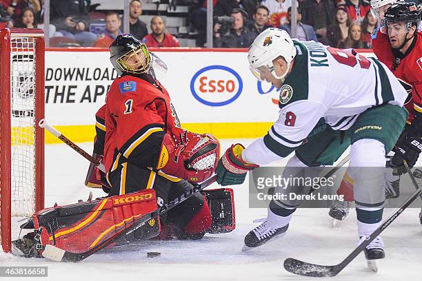 Jonas Hiller of the Calgary Flames stops the shot of Mikko Koivu of the Minnesota Wild during an NHL game at Scotiabank Saddledome on February 18,...