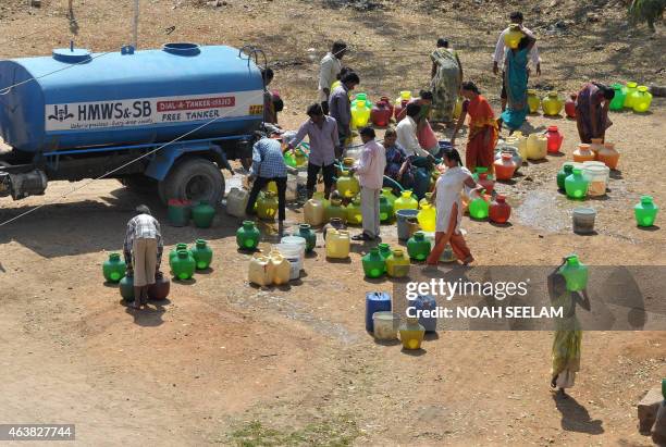 Indian residents fill containers with potable drinking water from a government water supply tanker at a slum in Hyderabad on February 19, 2015....