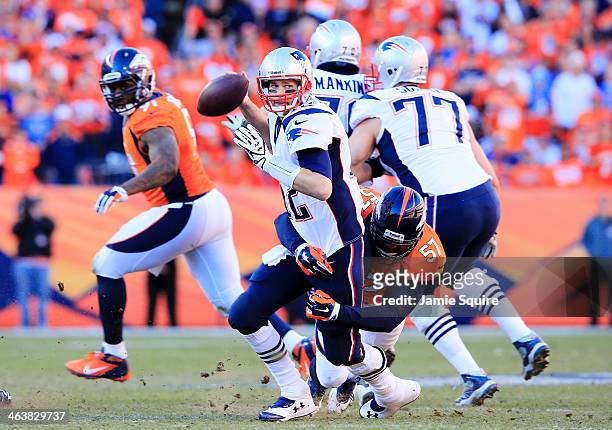 Tom Brady of the New England Patriots throws the ball away as he is hit by Jeremy Mincey of the Denver Broncos in the fourth quarter during the AFC...