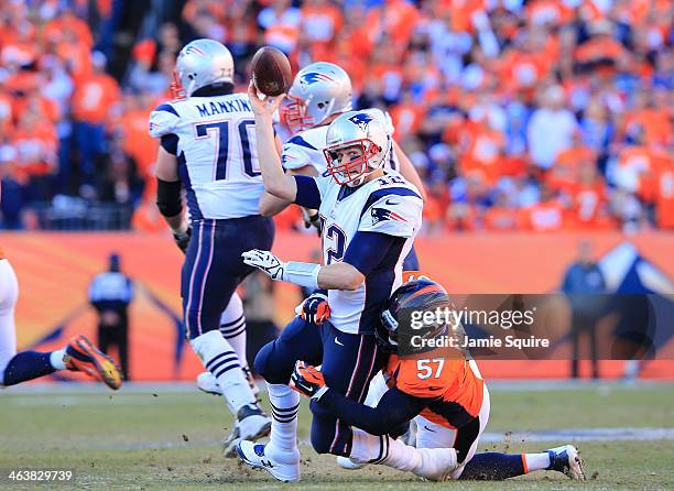 Tom Brady of the New England Patriots throws the ball away as he is hit by Jeremy Mincey of the Denver Broncos in the fourth quarter during the AFC...