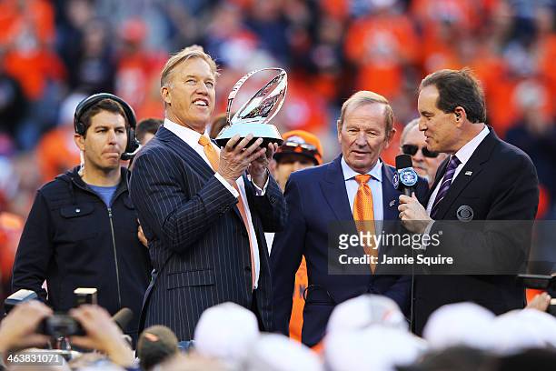 John Elway, executive vice president of football operations for the Denver Broncos, celebrates with the Lamar Hunt Trophy after they defeated the New...