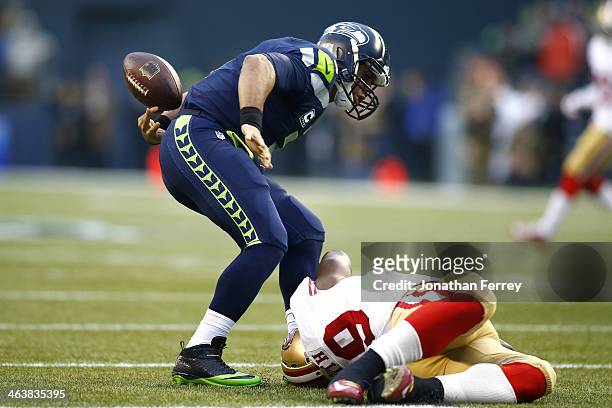 Quarterback Russell Wilson of the Seattle Seahawks fumbles the ball in the first quarter after being tackled by outside linebacker Aldon Smith of the...