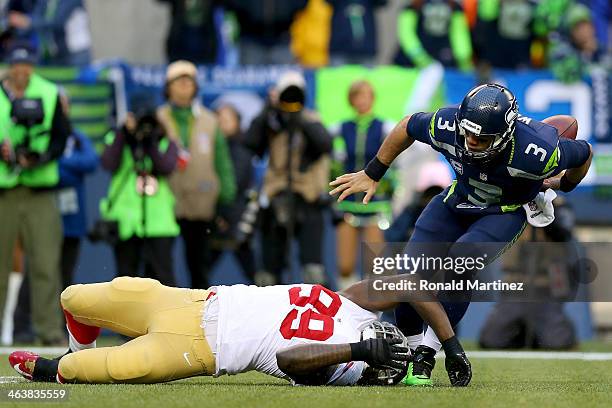 Quarterback Russell Wilson of the Seattle Seahawks fumbles the ball in the first quarter as he is tackled by outside linebacker Aldon Smith of the...