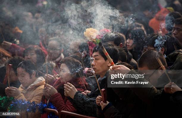 Chinese people hold incense while praying with others at the Yonghegong Lama Temple during celebrations for the Lunar New Year February 19, 2015 in...