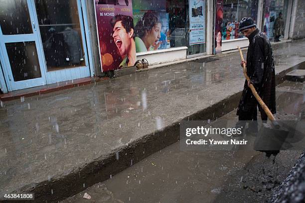 Kashmiri employee cleans a drain manually in the city centre during fresh snowfall on February 19, 2015 in Srinagar, Indian Administered Kashmir,...